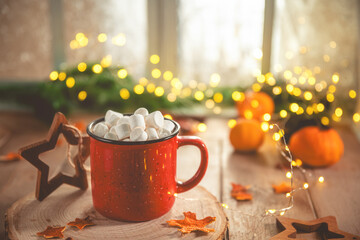 Cute cozy winter composition. red mug, marshmallows, oranges and Christmas lights.