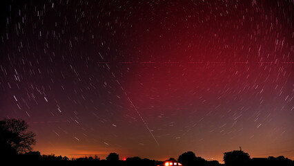 Long exposure of a Stable Auroral Red arc, or SAR arc, a rare space phenomenon over north east Oklahoma sky on November 5th, 2023; with star trails, airplane and satellite tracks crossing the sky - obrazy, fototapety, plakaty