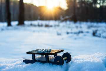 winter holiday background with a toy sled carrying a gift against the backdrop of snowy weather and...