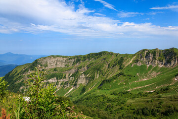 picturesque beautiful panorama view of the mountain gorge mountain ranges covered with greenery forests and snow against the background of the blue sky wide