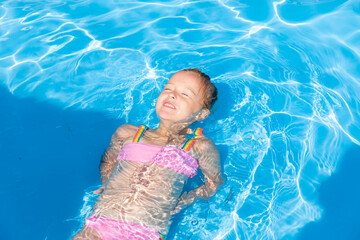 Child in swimming pool. Tropical vacation for family with kids. Little girl wearing swimsuit...