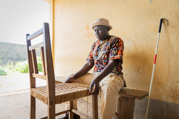 Blind African man busy finishing weaving dining chair.Blindness and handwork concept