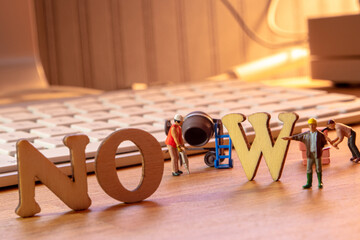 NOW word or concept made by wooden letters on wooden background with white keyboard in the...