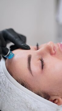 Hydrafacial treatment at work on female patient. Aesthetician performs hydro dermabrasion for skin rejuvenation. Clear, hydrate, exfoliate complexion. Beauty spa skincare, anti-aging procedure.