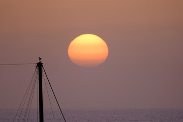A beautiful bright sunset on the ocean, a huge sun setting behind the horizon against the...