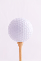 Golf Ball Close-up On Wooden Tee Against Light Backgournd