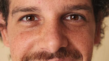 Obraz premium Detailed close-up shot of man's opening eye and looking at camera in studio on beige background