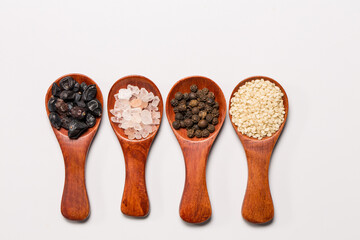 Many different spices in wooden spoons, background with different spices, spices on a white background