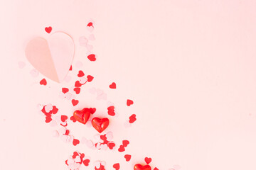 Valentines day festive background with scattred pink and red hearts over pink background with copy space