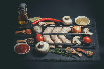 Raw barbecue sausages with different spices and vegetables, raw sausages and raw vegetables,...