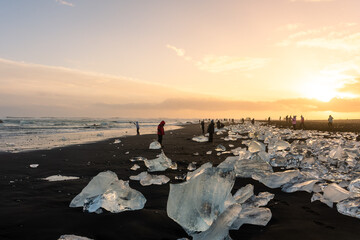 Tourists admiring the sunset in the Diamond beach, volcanic beach with icebergs, Iceland