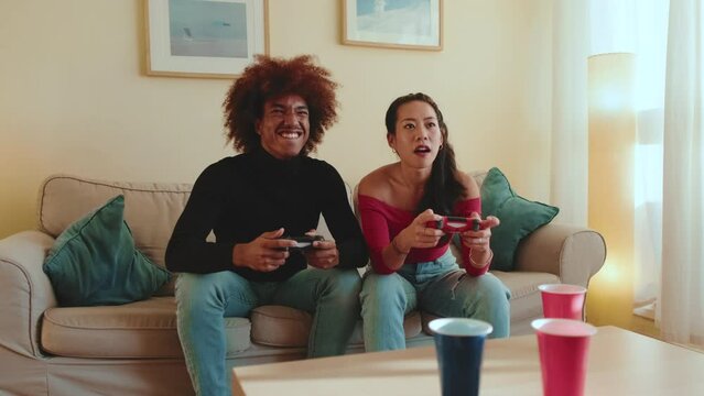 Young people playing video games on console while sitting on the couch