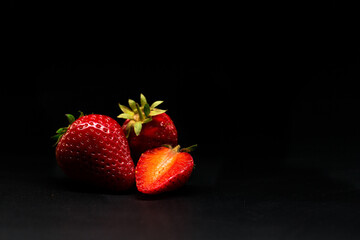 Red strawberries on a black background, sweet strawberry