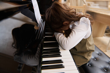 Cute little girl folds her hands and hid her face, feeling sadness, having difficulties or forced...