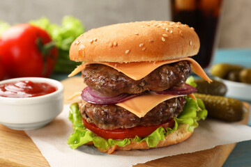 Tasty hamburger with patties, cheese and vegetables served on table, closeup