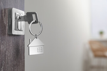 Mortgage and real estate. Open door with key and house shaped keychain against blurred background, space for text