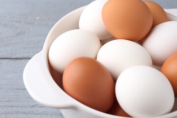 Unpeeled boiled eggs in saucepan on grey wooden table, closeup