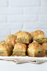 Delicious fresh baklava with chopped nuts on white table, closeup. Eastern sweets