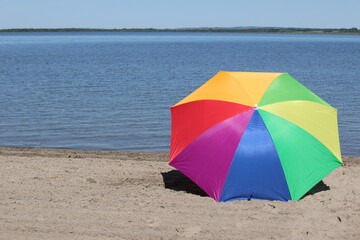 Summer time beach and vacation vibes created by a vibrant rainbow colored umbrella lying on the...