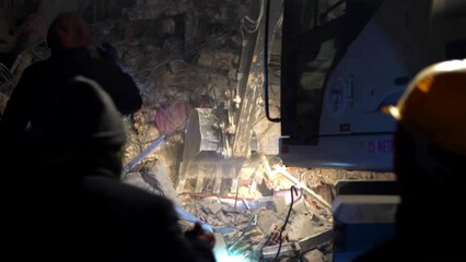 Volunteers and rescue teams evacuated and searched for victims who were still buried and trapped in building rubble using heavy equipment such as excavators at night. Events after a major earthquake
