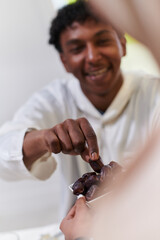 African American Muslim man delicately takes dates to break his fast during the Ramadan month, seated at the family dinner table, embodying a scene of spiritual reflection, cultural tradition, and the
