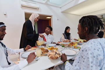 In the sacred month of Ramadan, a Muslim family joyously comes together around a table, eagerly awaiting the communal iftar, engaging in the preparation of a shared meal, and uniting in anticipation