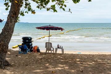 People on the urban sandy beach of a tropical resort. A beach lifeguard sleeps on a chair in the...