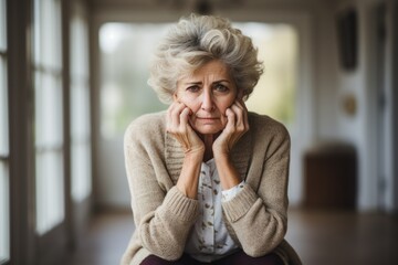 Senior woman with depression sitting with her head in her hands at home - obrazy, fototapety, plakaty