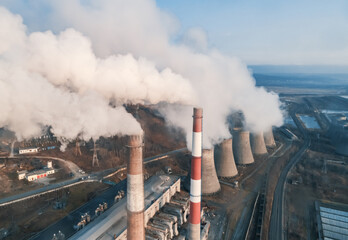 Aerial view of tall chimney pipes with grey smoke from coal power plant. Production of electricity...