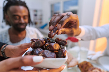In a poignant close-up, the diverse hands of a Muslim family delicately grasp fresh dates,...