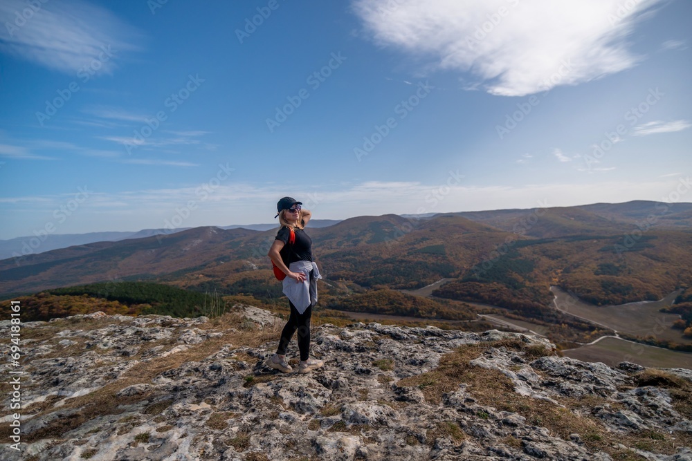 Wall mural woman backpack on mountain peak looking in beautiful mountain valley in autumn. Landscape with sporty young woman, blu sky in fall. Hiking. Nature