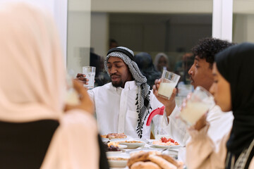 A traditional and diverse Muslim family comes together to share a delicious iftar meal during the...
