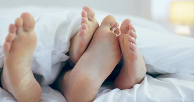 Closeup, playful and feet of a couple in a bed for comfort, intimacy and sleeping with love. House, care and legs of people in the bedroom with a blanket for playing or relax in the morning together