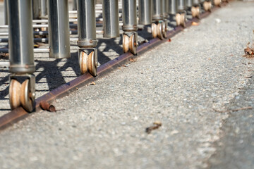 Detailed view of the undercarriage of several shopping carts, showing their wheels and the guiding rail on a paved ground.