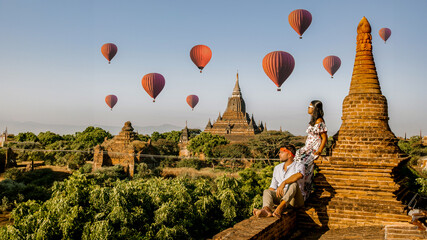 Bagan Myanmar, a couple of men and women looking at the sunrise on top of an old pagoda temple. a...
