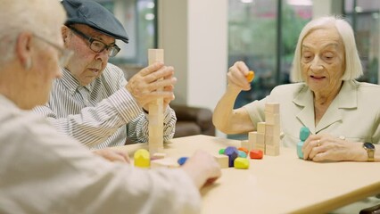 Concentrated seniors resolving brain skill games with wooden pieces in geriatric