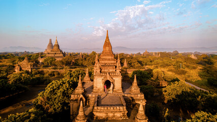 Bagan Myanmar, a couple of men and women are looking at the sunrise on top of an old pagoda temple....