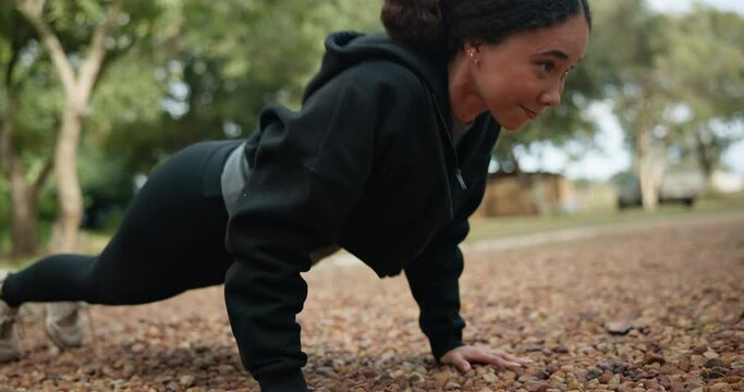Woman, fitness and push ups in nature for workout, exercise or strength training in the outdoors. Determined female person exercising and lifting body on ground or floor for healthy wellness outside