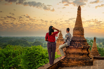 Bagan Myanmar, a couple of men and women looking at the sunrise with a foggy landscape on top of an...
