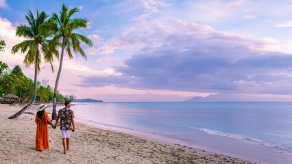 couple on the beach with palm trees watching the sunset at the tropical beach of Saint Lucia or St Lucia Caribbean Island. men and women on vacation in St Lucia a tropical island with palm trees - obrazy, fototapety, plakaty