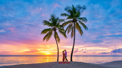 couple on the beach with palm trees watching the sunset at the tropical beach of Saint Lucia or St Lucia Caribbean Island. men and women on vacation in St Lucia a tropical island 