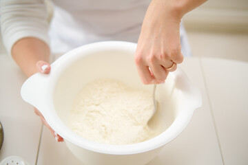 Closeup on woman's hands mixing flour in a bowl at home. Process of cooking pecan pie in home kitchen for American Thanksgiving Day.