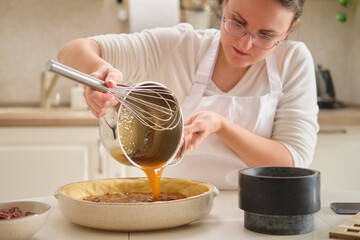 A woman pours corn syrup for the filling of a pecan pie. Process of cooking pecan pie in home...