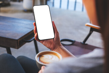 Mockup image of a woman holding mobile phone with blank desktop screen while drinking coffee in cafe - Powered by Adobe