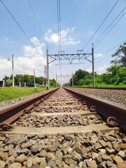 Morning landscape on the railway tracks with trees and grass on its side and white clouds during daylight perfect for industrial concept background