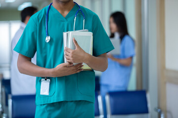 Portrait of medical student arms crossed holding learning book have group students on background in...