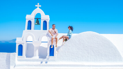 A couple watching the sunset on vacation in Santorini Greece, men and women visit the Greek village...