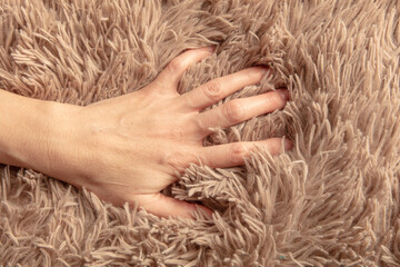 A woman's hand on a beige carpet with lint