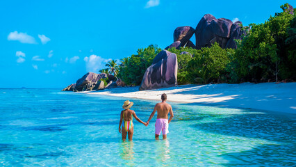 Anse Source d'Argent beach La Digue Island Seychelles, a couple of men and woman walking at the beach at a luxury vacation. a couple swimming in the turqouse colored ocean - obrazy, fototapety, plakaty