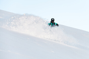 One-armed male skier descends a snowy slope and the snow flies in directions